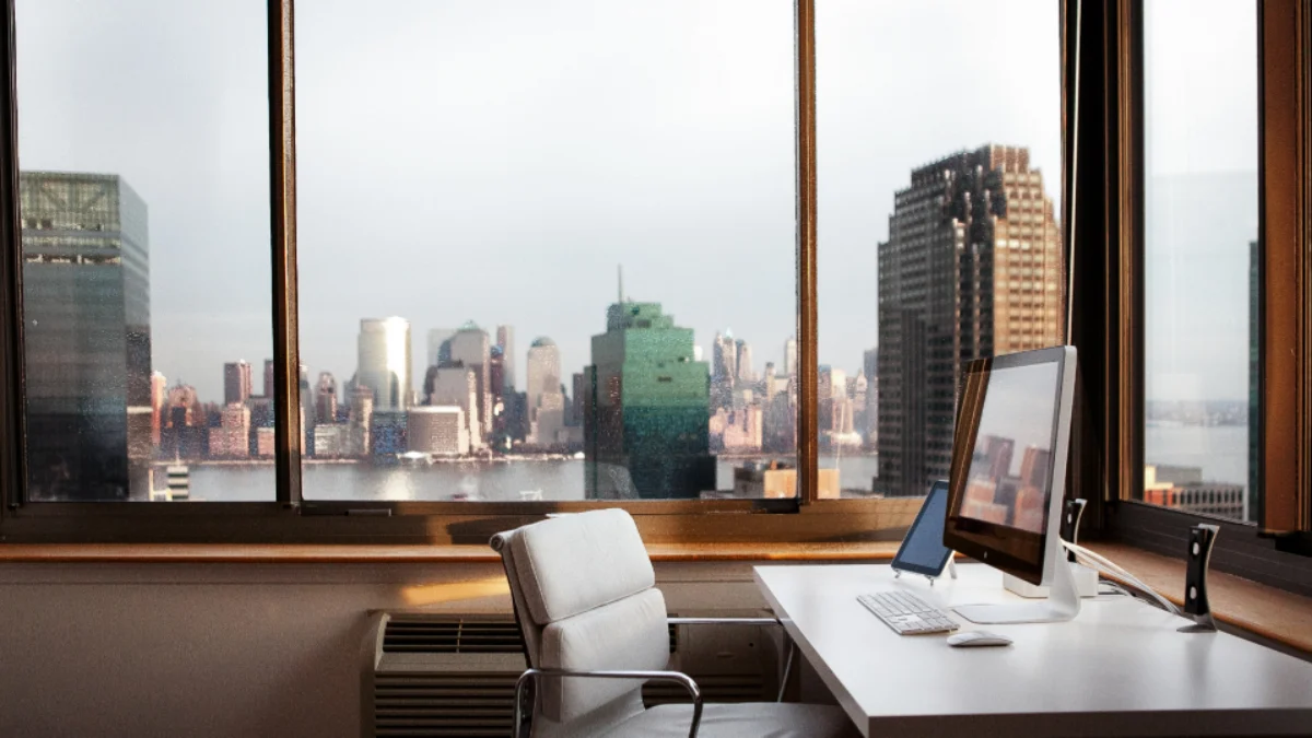 Escritório moderno e organizado com mesa de trabalho, computador e vista urbana ao fundo